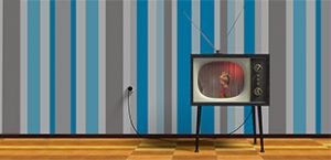 A 1950s TV sits on a wood floor in front of blue and gray striped wallpaper, playing a burlesque performance