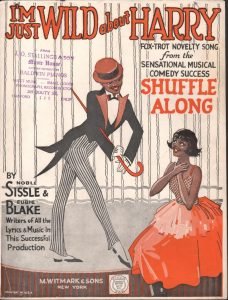 Cover page of printed sheet music for "I'm Just Wild About Harry". Features lithographed image of well-dressed black man with cane and tails standing next to a black woman in red gown, apparently kneeling.