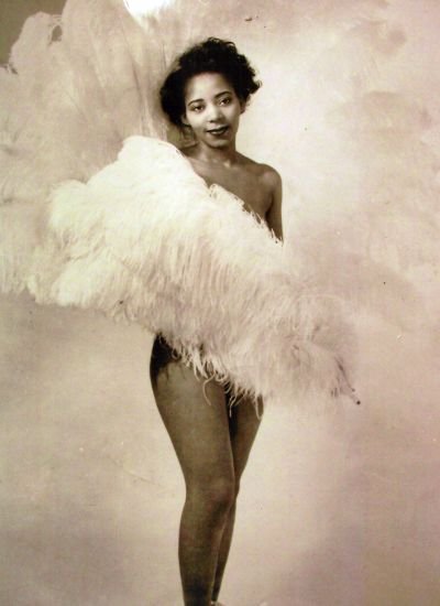 Jean Idelle poses with white feather fans in front of her